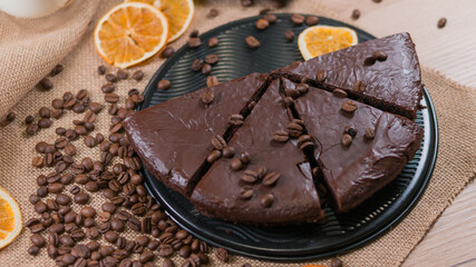 slices of chocolate brownie cake with glass of milk and coffee beanas on wooden table