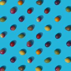 Pattern created of different candy marzipan fruit organized on isometric grid. Flat lay cyan color setting with orange, green, yellow, dark blue, purple candies.