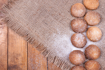 cookies are folded in two rows and sprinkled with a little white powder, on a gray rug with fringes around the edges, against a background of wooden boards