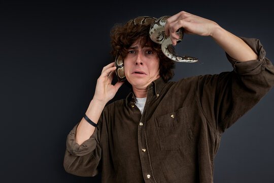 man has a panic, he is trying to remove a live snake from himself, stand at a loss isolated on black background