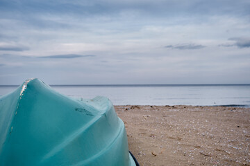 Turquoise fishing boat on the beach with sea and sky background.