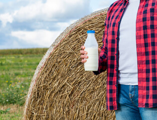 man drinks fresh bio milk on the field in the background, hay, grass, farm