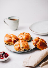 Traditional English Easter Hot Cross Buns on a plate with jam and tea cup
