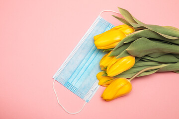 Blue medical mask and yellow tulips on pink background, thanks to doctors concept