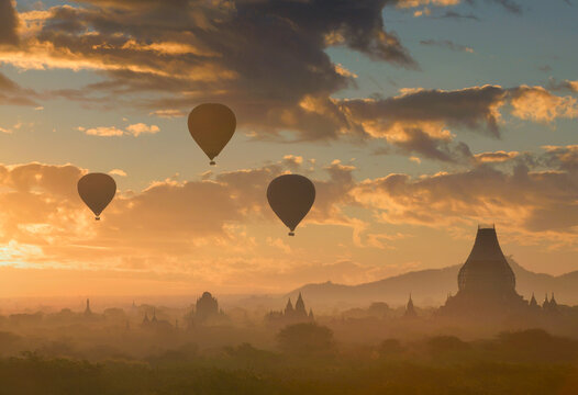Silhouette of hot air balloons flying over temples at sunset, Bayan, Myanmar