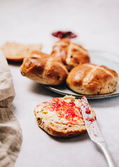 Close up of traditional easter hot cross bun with butter and jam