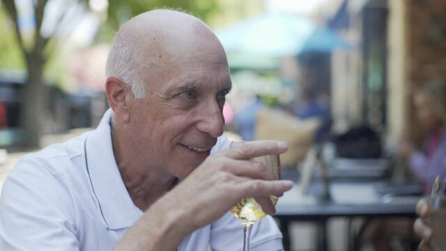 Caucasian Man at a Restaurant Drinking From a Wine Glass and Talking