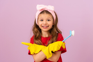 A happy little girl keeps the house clean. rubber gloves and a scrub brush.