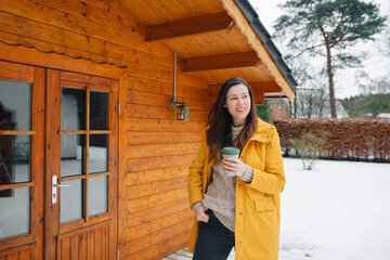 Woman in yellow jacket is happy and holds a cup of tea in hand. Drink tea outside in the morning....