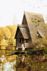 Wooden whimsical cozy house in the autumn park near the lake and a couple in love