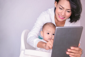  Asian mother and child are looking at the tablet with interest and smiling, focusing on