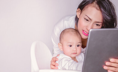  Asian mother and child are looking at the tablet with interest and smiling, focusing