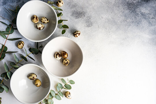 Easter table setting with bowls of Easter eggs and eucalyptus stems