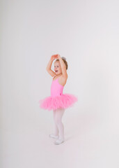 little blonde ballerina in a pink tutu dress dances on a white background with a place for text