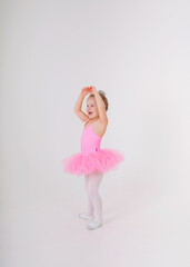 little blonde ballerina in a pink tutu dress dances on a white background with a place for text