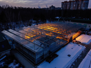 Glowing modern glass greenhouse in winter night, aerial view