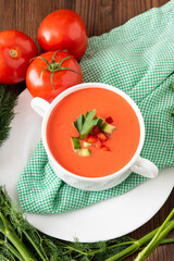 Delicious tomato soup with herbs on a wooden background. Top view.