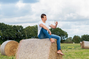 man drinks fresh bio milk on the field in the background, hay, grass, farm