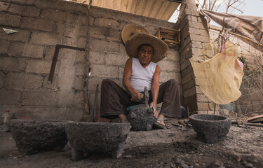 Craftsman working in his workshop, carving the stone to make molcajetes, traditional Mexican crafts...