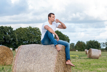 man drinks fresh bio milk on the field in the background, hay, grass, farm