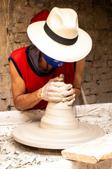 Man making ceramic articles on the pottery wheel in a traditional factory in the city of Ráquira...