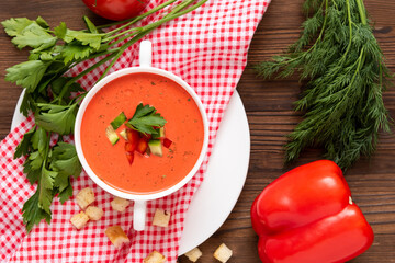 Spanish tomato gazpacho soup made from fresh tomatoes with various spices and herbs on a wooden background.