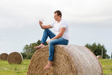 man drinks fresh bio milk on the field in the background, hay, grass, farm