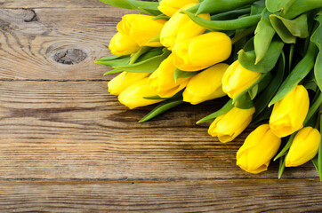 Yellow tulips lie on an old wooden surface