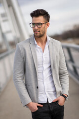 Yuppie standing on the bridge. Portrait of young businessperson with glasses outdoors