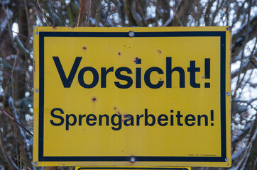 Yellow sign reading caution blast on german
