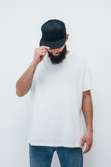 Young bearded hipster guy wearing white oversized blank t-shirt on a white background. Mock-up for...