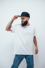 Young bearded hipster guy wearing white oversized blank t-shirt on a white background. Mock-up for print. T-shirt design and advertising concept.