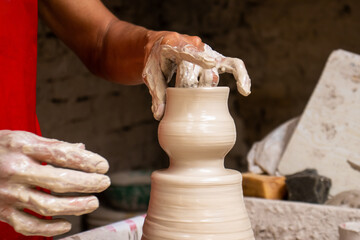 Man making ceramic articles on the pottery wheel in a traditional factory in the city of Ráquira...