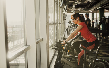 Active fitness woman training in gym, riding a stationary exercise bike