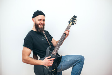 Stylishly dressed rock musician with a beard plays electric guitar
