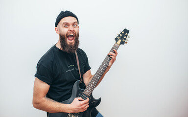 Stylishly dressed rock musician with a beard plays electric guitar