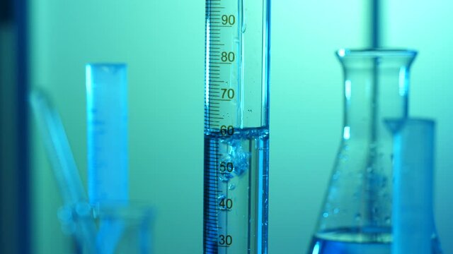 In a laboratory, filling up a graduated cylinder tube with a liquid