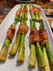 bacon wrapped asparagus on a white plate