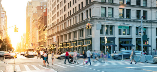 Crowds of people in motion walking across the busy intersection on 5th Avenue in Midtown Manhattan,...