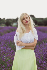 The young attractive woman is standing in the lavender field