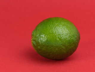 A single green lime on a red background