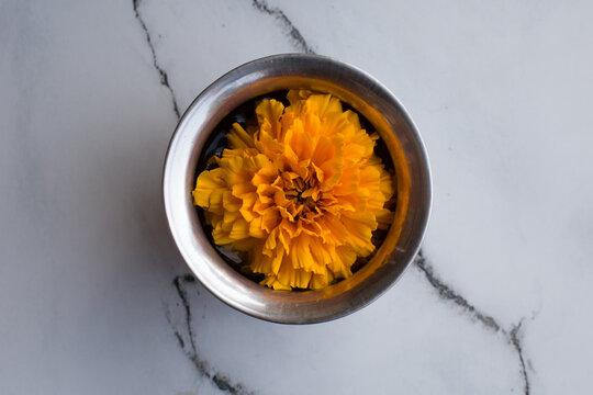 picture of steel lota with water and marigold flower inside of it used in religious places