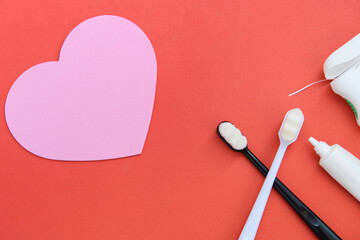 Two toothbrushes black and white handles and toothpaste and dental floss on red background. Valentines day concept.