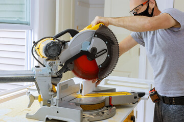 The worker is using personal protective equipments for healthcare covid-19, man cut on the wooden molding with circular saw