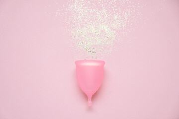 Menstrual cup with glitter on pink background. Alternative feminine hygiene product during the period. Women health concept