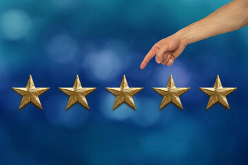 male client's hand shows five gold foil star on blue background, concept of evaluating the result,...
