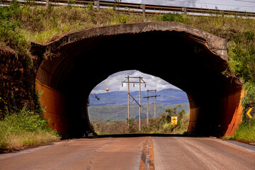 Túnel cênico em estrada do interior de Minas Gerais, com torres de energia e mares de morros ao...