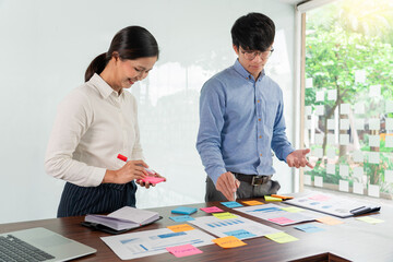 Creative group of business people brainstorming use sticky notes picking to share idea on table decision Choosing Concept for developing plan in business conference room.