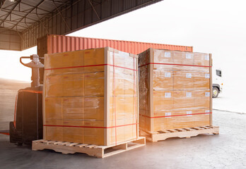 Cargo shipment loading for truck. Freight truck for delivery service. Warehouse dock load pallet goods into container truck. Stacked boxes wrapped plastic on pallet rack.