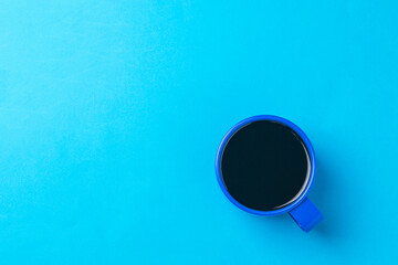 Top view of a cup of black coffee on a bright blue background.